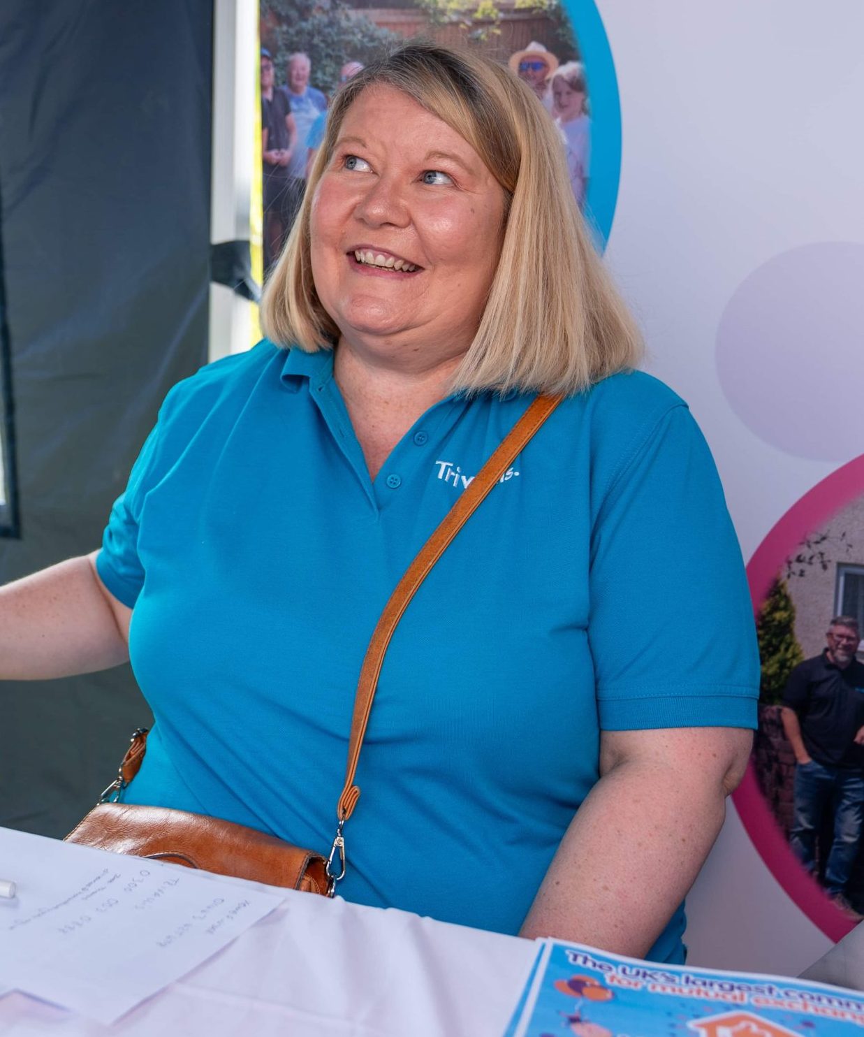 Trivallis Housing Landlord Wales A cheerful woman in a blue polo shirt engaged in a light-hearted conversation at a Trivallis Community Housing event booth.