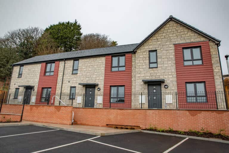 Trivallis Housing Landlord Wales Newly built semi-detached houses with brick and colorful cladding, featuring parking spaces in the foreground by Trivallis Community Housing.
