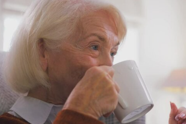 Trivallis Housing Landlord Wales An elderly woman with white hair drinking from a white mug in her Trivallis RCT housing.