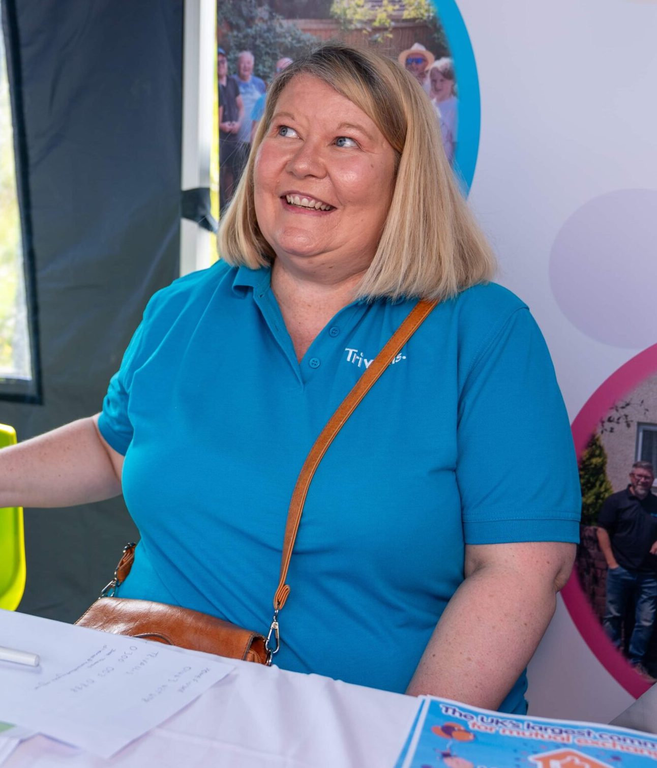 Trivallis Housing Landlord Wales A smiling woman in a blue polo shirt engaging in a cheerful conversation at the Trivallis Community Housing event booth.