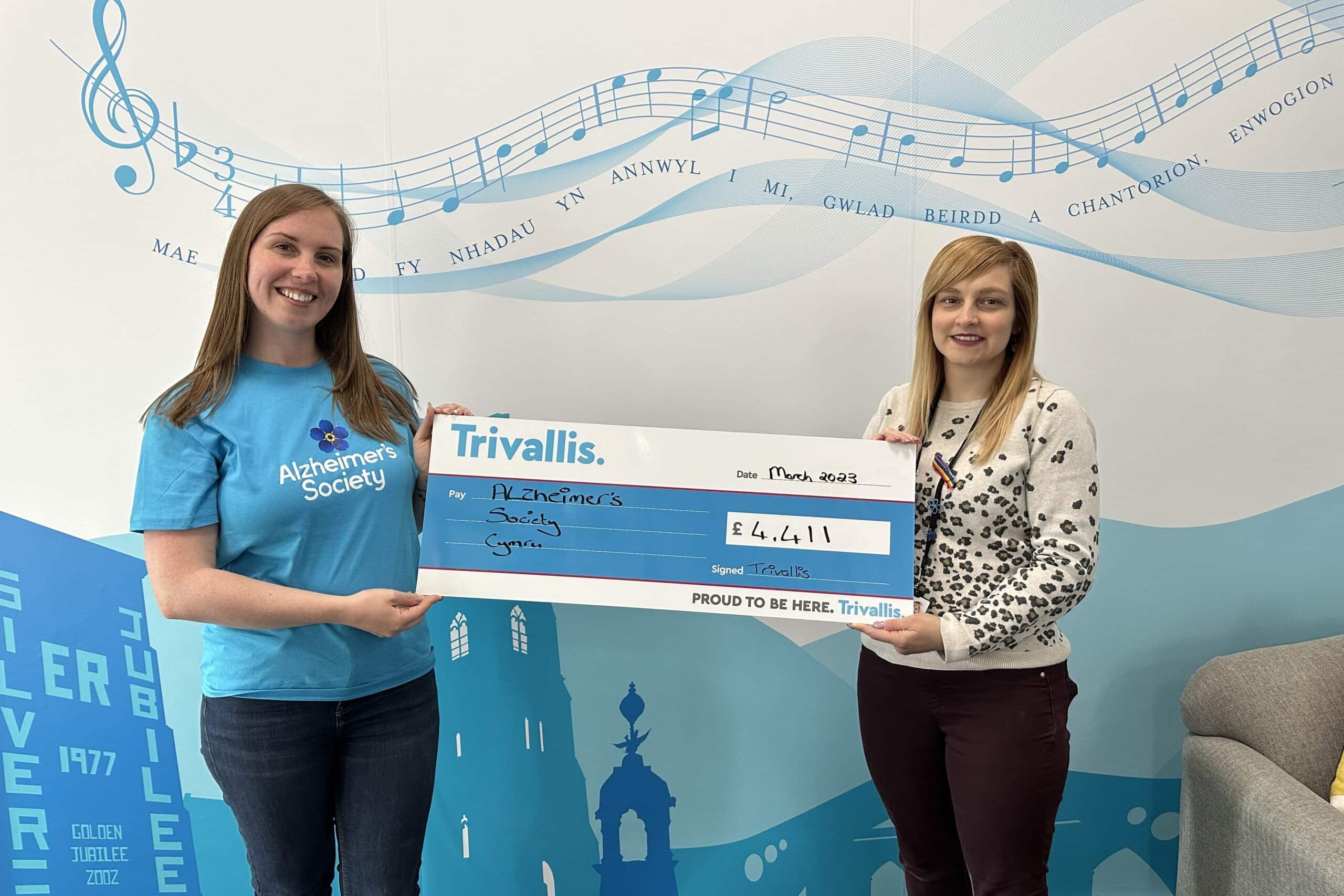 Trivallis Housing Landlord Wales Two individuals from Trivallis Community Housing proudly presenting a large charity check for £4,411 to the Alzheimer's Society.