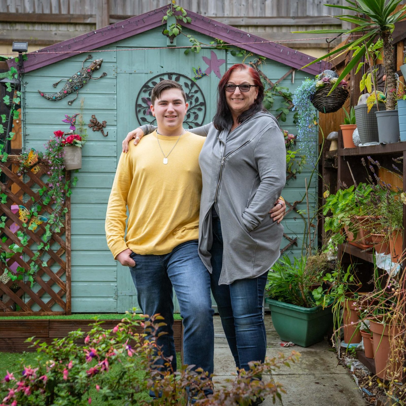 Trivallis Housing Landlord Wales A woman and a young man standing together in a Trivallis garden full of plants, smiling at the camera.