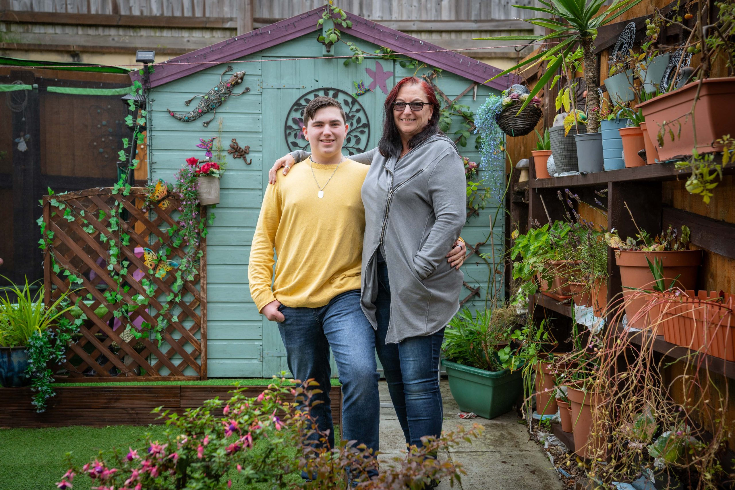 Trivallis Housing Landlord Wales A woman and a young man standing together in a Trivallis garden full of plants, smiling at the camera.