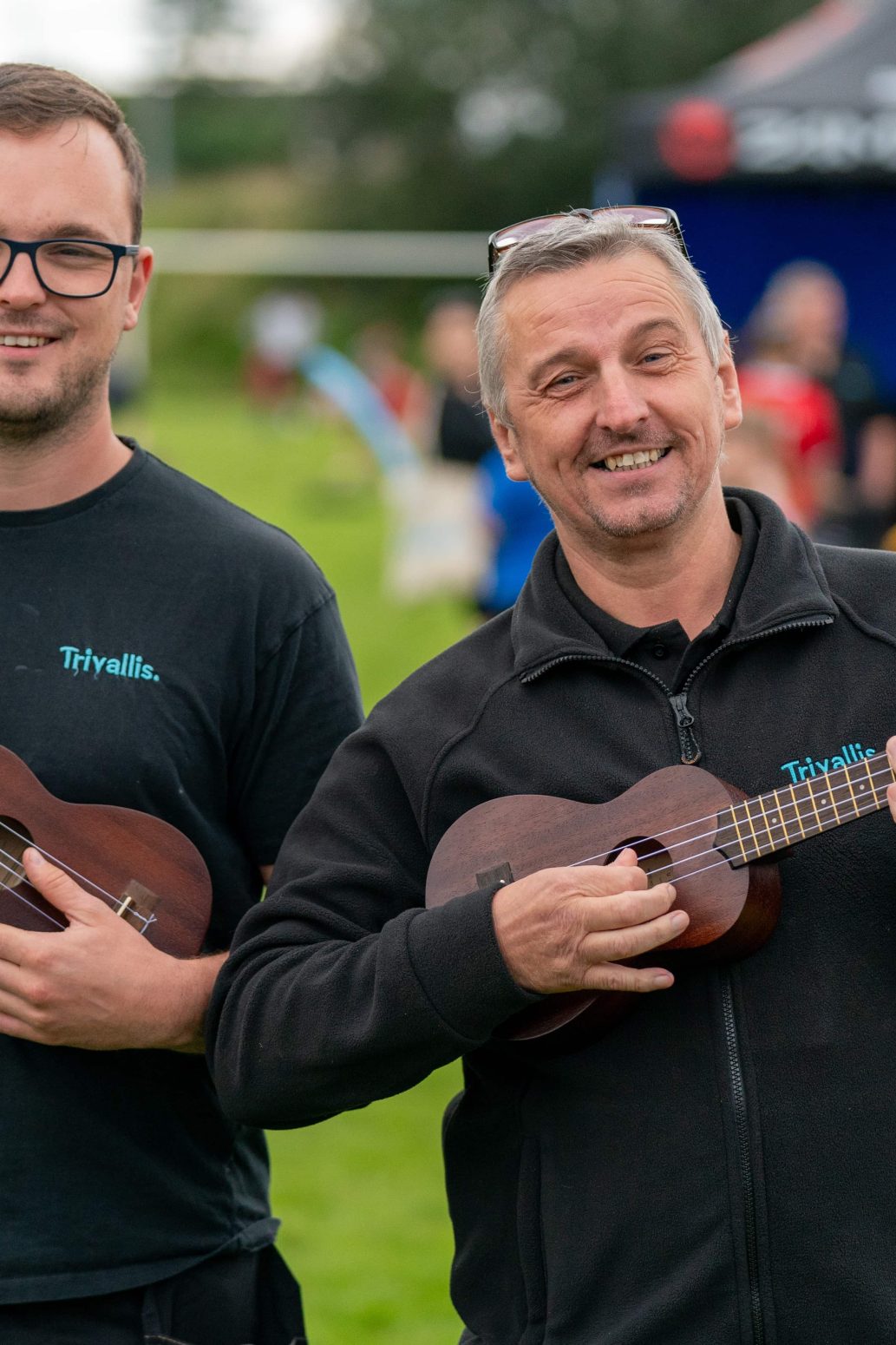 Trivallis Housing Landlord Wales Two men holding ukuleles and smiling at a Trivallis outdoor event.